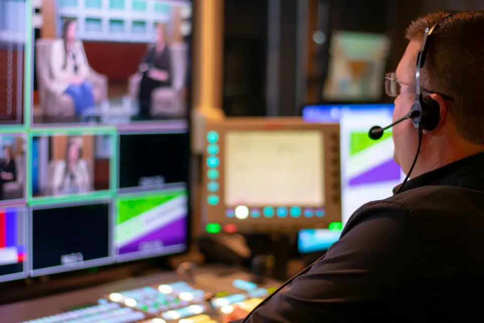 Director in a headset working at the monitor wall of a broadcast control room