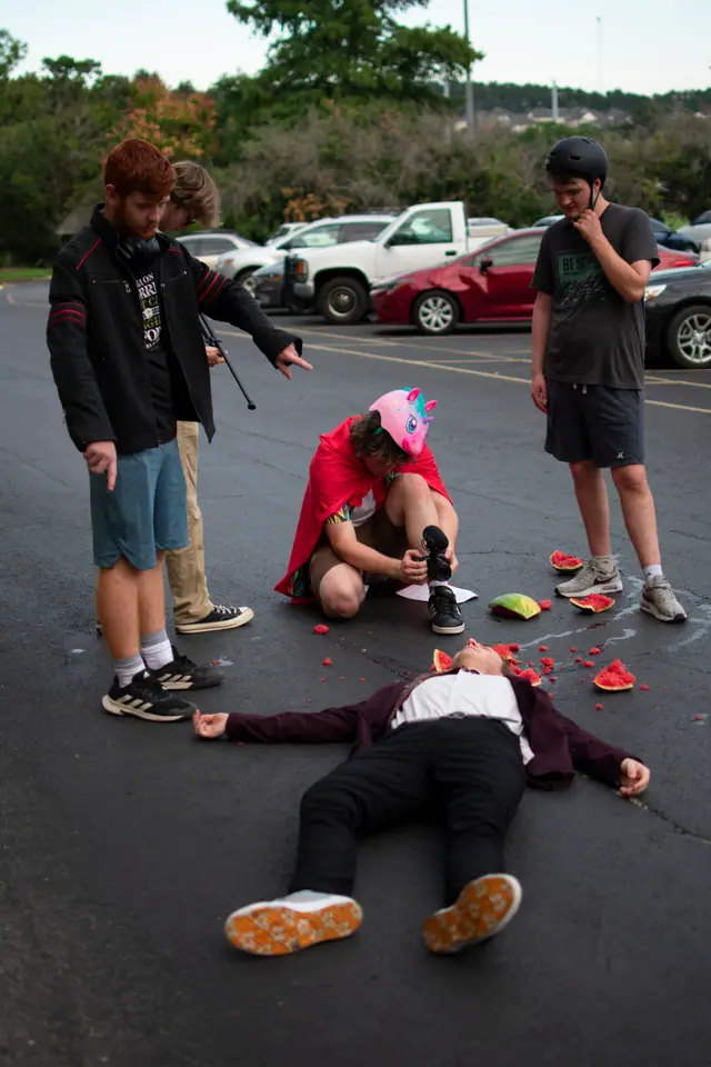 Crew members standing over a staged scene, reviewing the setup between takes