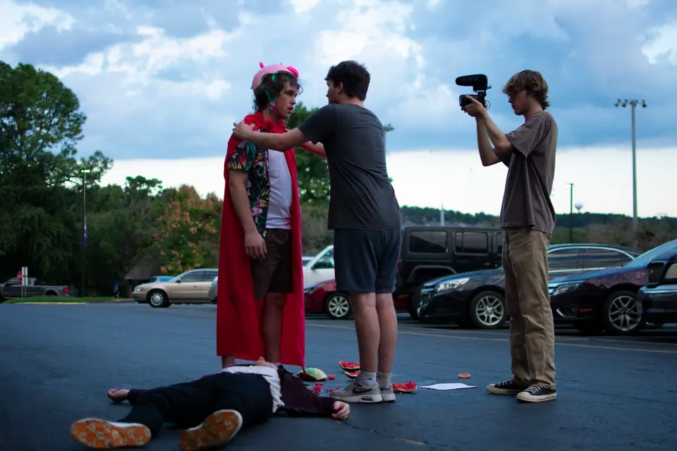 Operator shooting a handheld take of two actors on a rooftop set