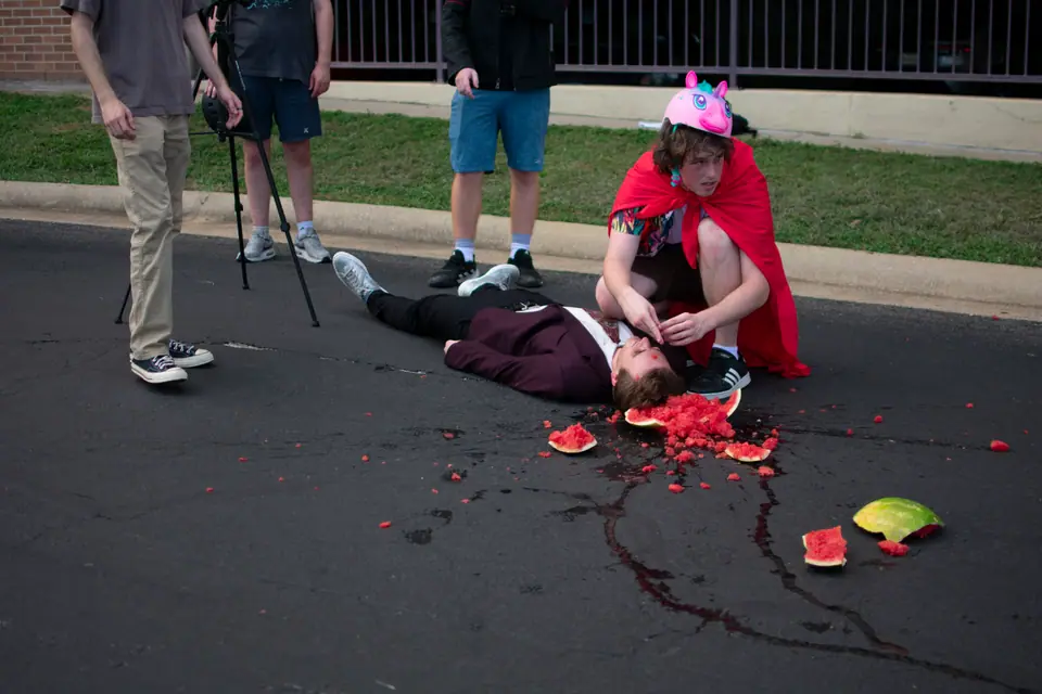 Crew gathered around a staged practical effect on set, actor on the ground mid-scene