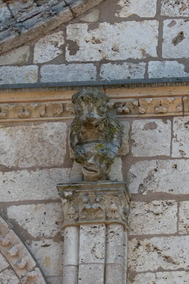 Weathered carved head set on a corbel against the cathedral's limestone wall