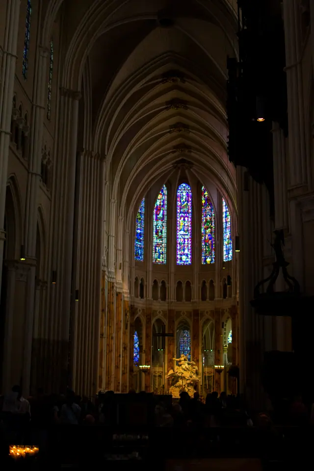 The nave of Chartres Cathedral looking toward the apse, stained glass above the lit high altar