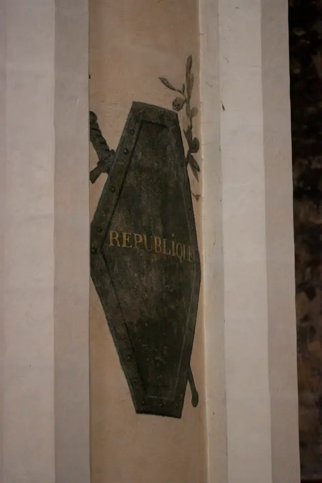 Weathered bronze plaque lettered République mounted on a pale stone wall