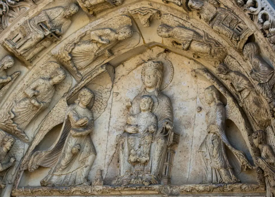 Carved tympanum of the Virgin and Child flanked by censing angels over a cathedral portal