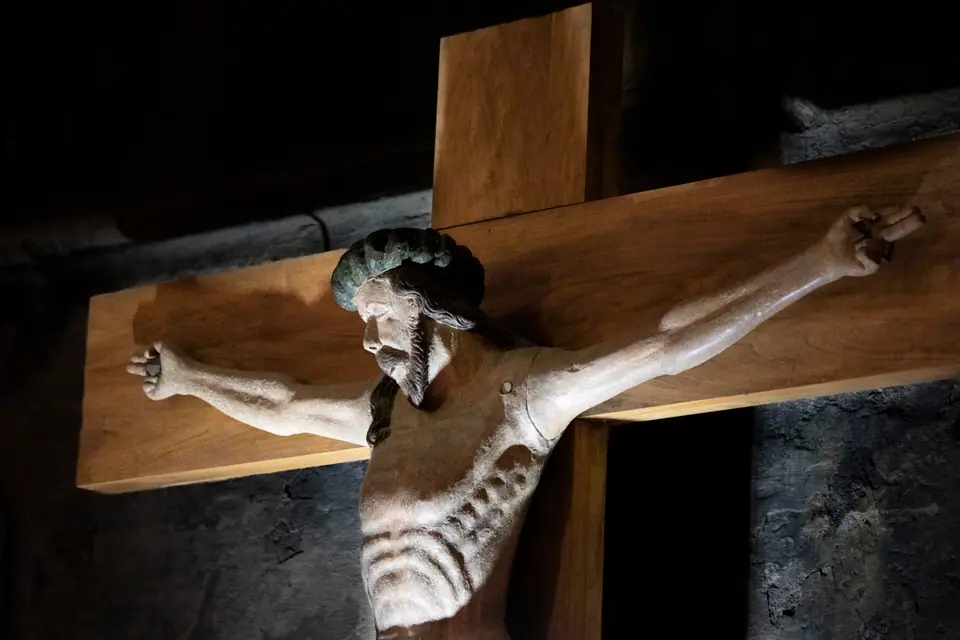 Carved wooden crucifix mounted against rough cathedral stonework