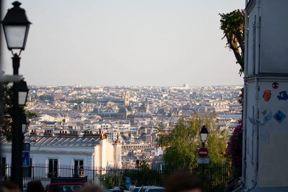 Paris rooftops stretching to the horizon, seen past an ornate cast-iron streetlamp