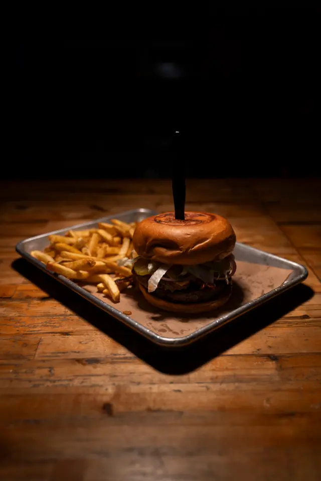 Stacked burger and french fries served together on a metal tray