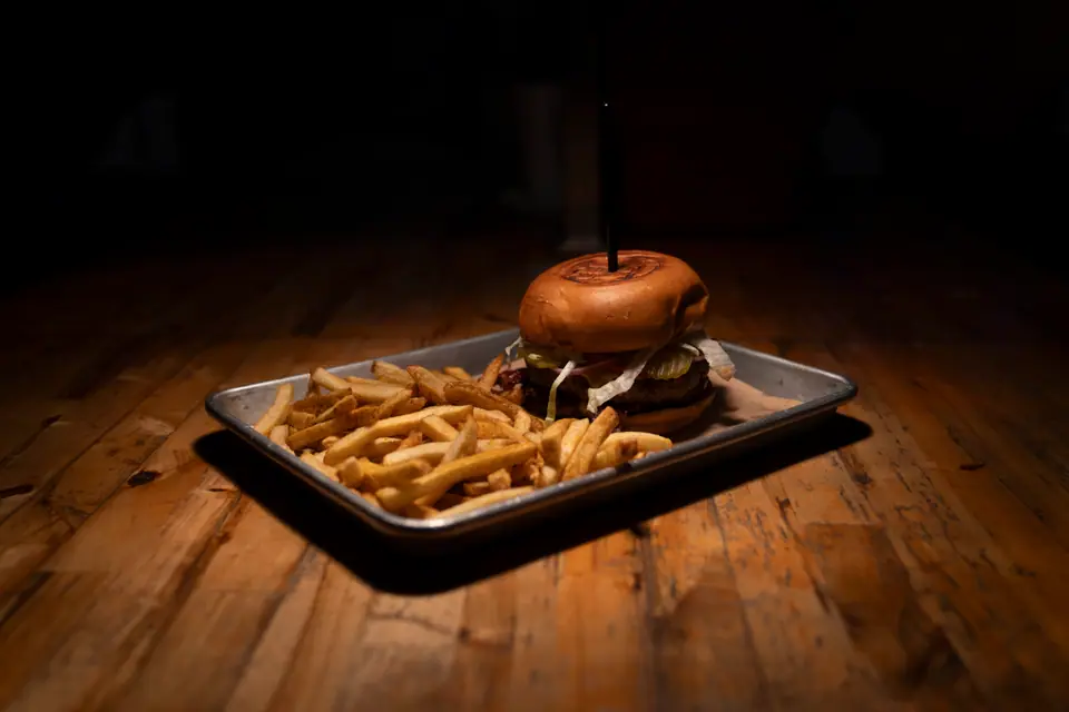 Low-angle photograph of a burger and fries on a tray, dark background