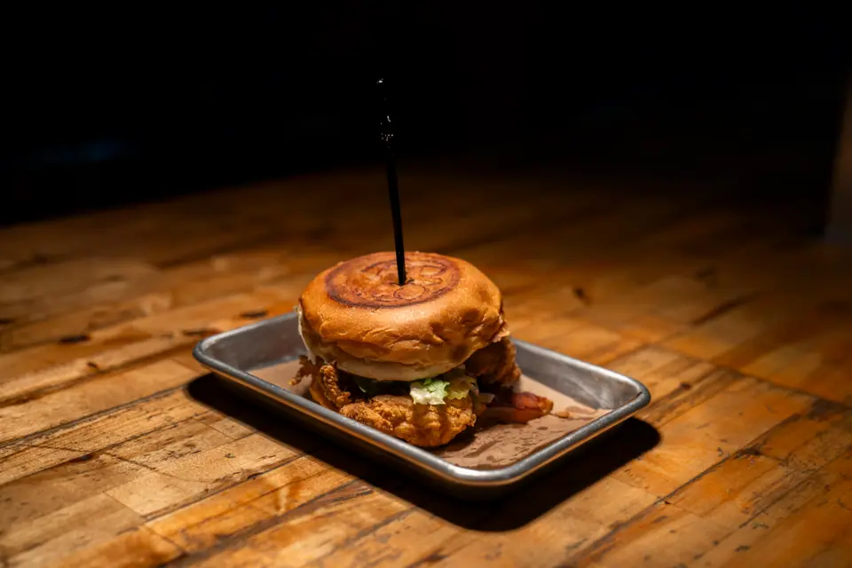 Cheeseburger on a metal serving tray under warm directional light