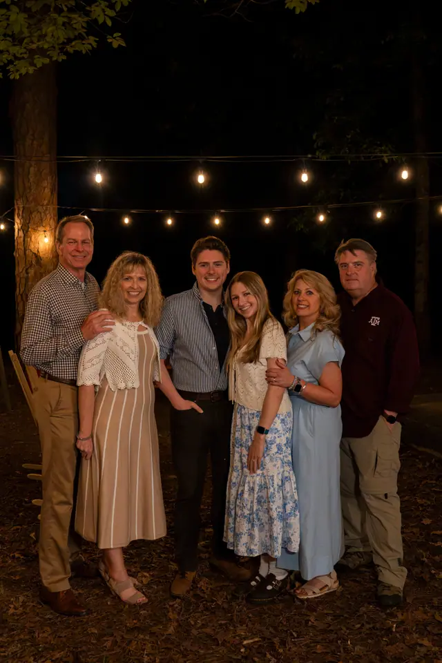 Family group portrait at night beneath string lights strung between trees
