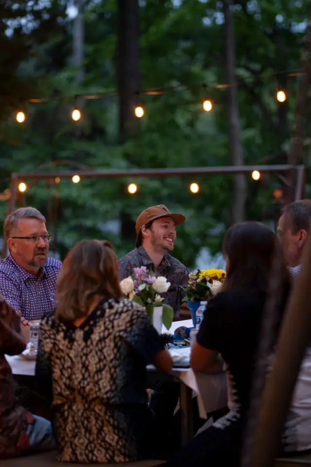 Events — Guests seated at a long table under warm string lights at an outdoor evening reception