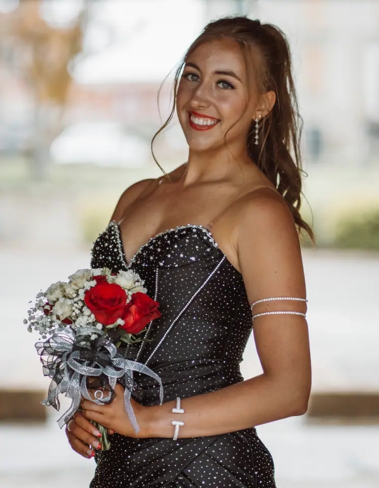 Portraits — Smiling young woman in a black sequined strapless prom dress holding a bouquet of red and white roses