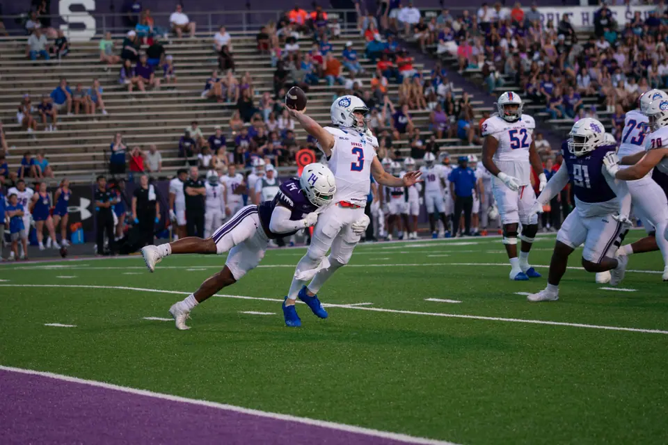 Receiver leaping for a catch during a college football game as defenders close in